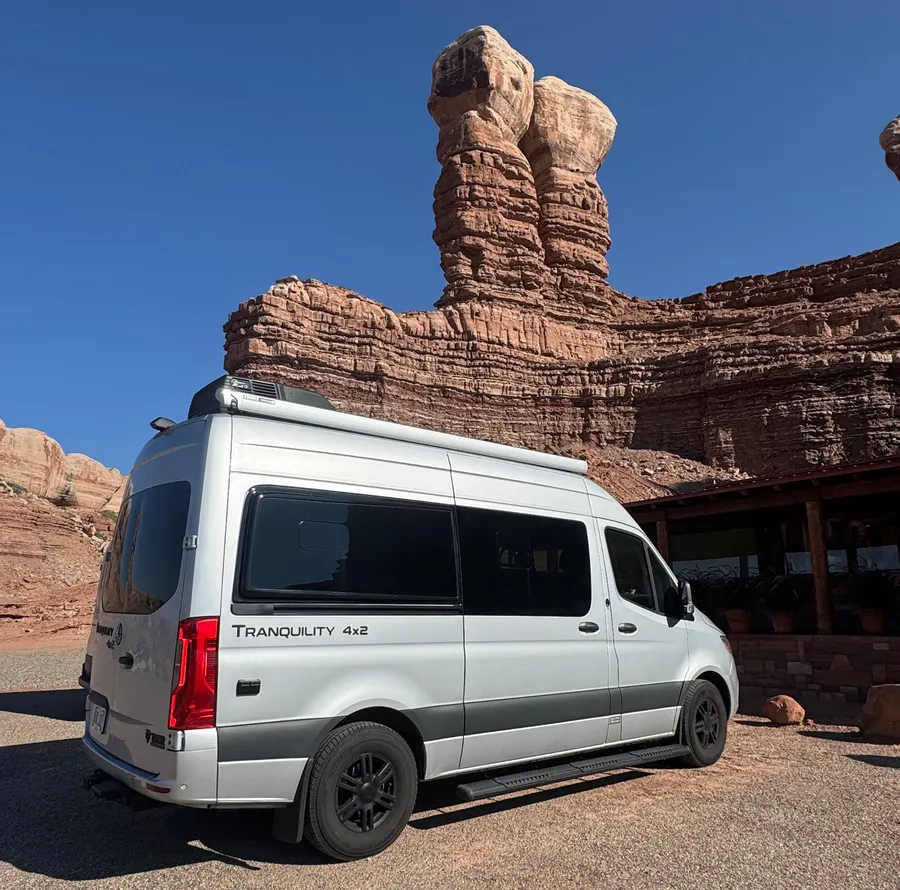 Wetiko's camper van parked beneath desert rock formations on the road